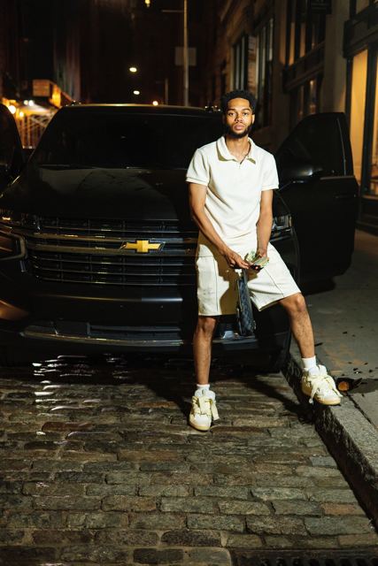 The CEO seated on a cobblestone street in front of a black SUV at night