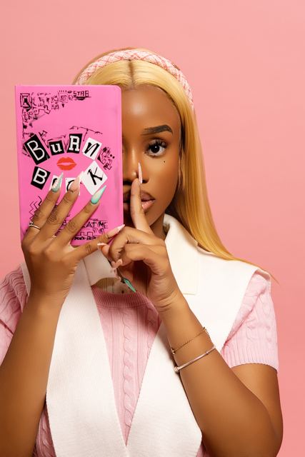 Model in pink peeking over a Burn Book